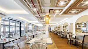 Un restaurant spacieux avec de hauts plafonds, des conduits apparents et un mélange de mobilier en osier et en bois.