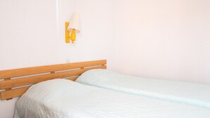 Een enkel bed met een houten hoofdbord en een lichtgekleurd dekbed.