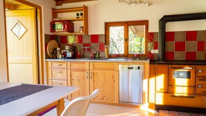 A kitchen with wooden cabinets, a dishwasher, a microwave, and a stove. - Alpenchalet Sachrang für 2 Personen (Sachrang)