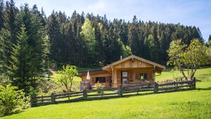 A wooden cabin with a porch, surrounded by a wooden fence and lush greenery. - Alpenchalet Sachrang für 2 Personen (Sachrang)