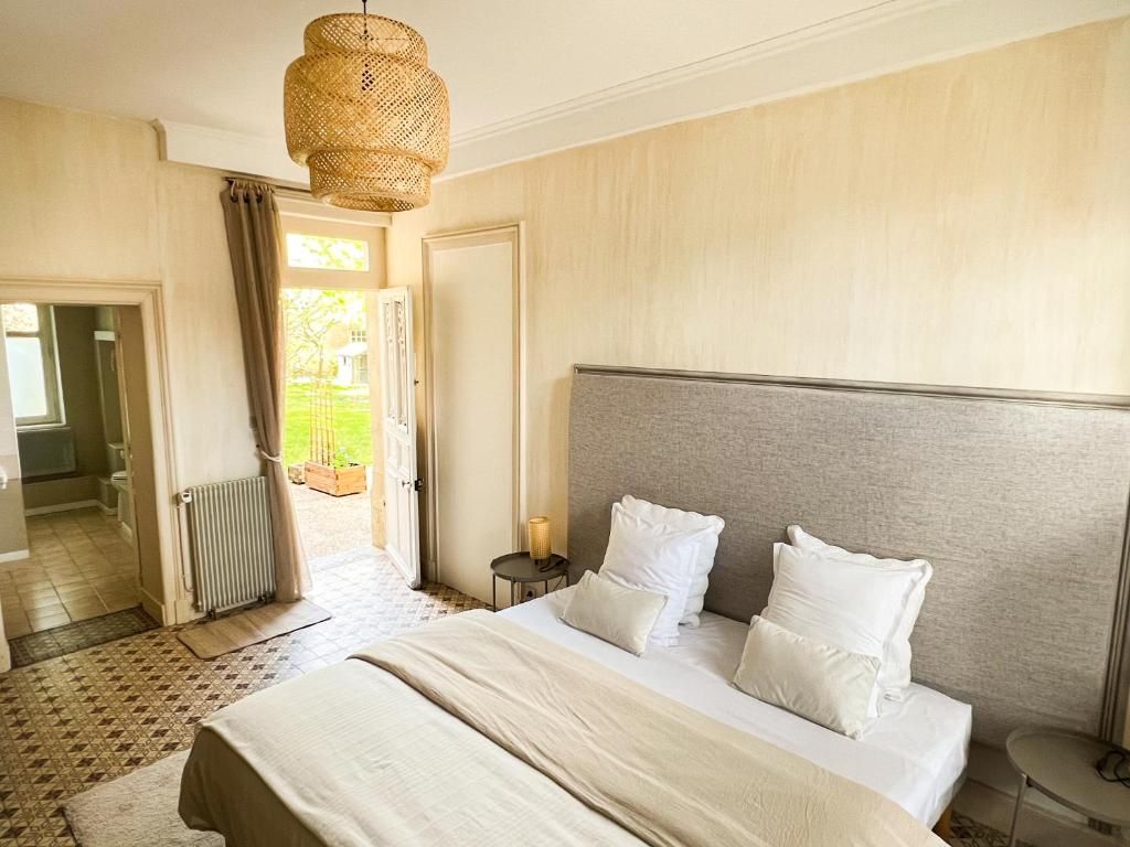 Habitación de hotel con una cama grande, una mesita de noche, una lámpara colgante y una puerta abierta que da a un balcón.