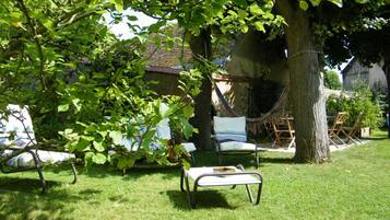 A garden with a hammock, a small table, and chairs under a tree.