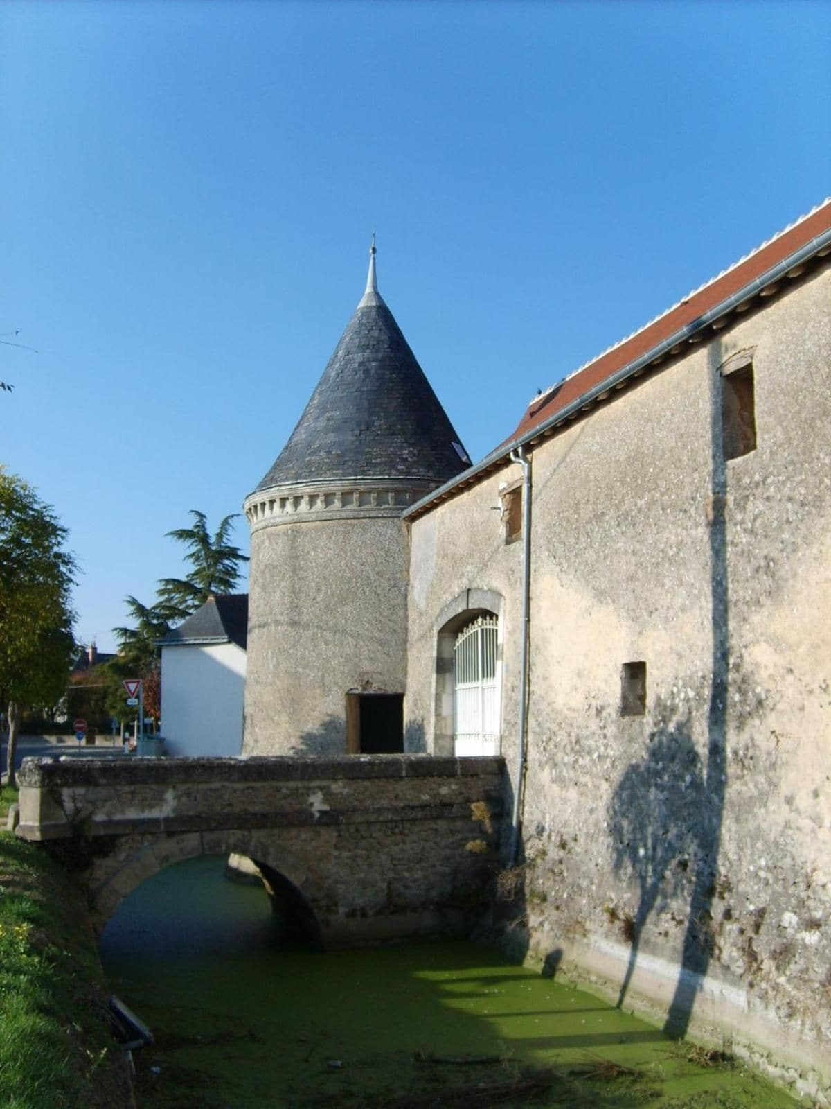 Un bâtiment en pierre doté d’une tour, d’un pont et d’un canal.