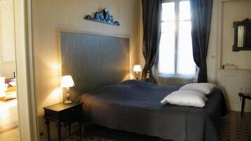 Une chambre d’hôtel avec un lit, deux lampes de chevet, une fenêtre avec des rideaux et un radiateur.