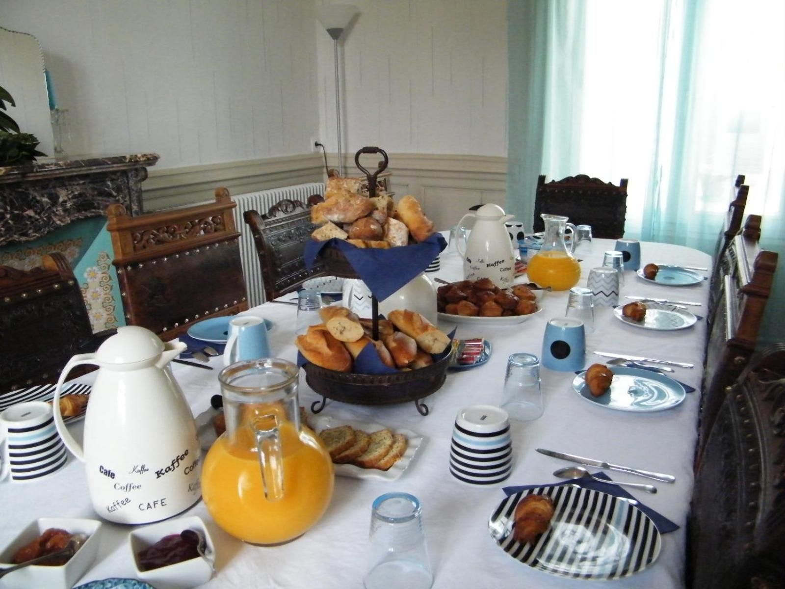 Ett matbord dukat med frukosttillbehör, inklusive bakverk, bröd och kaffe.