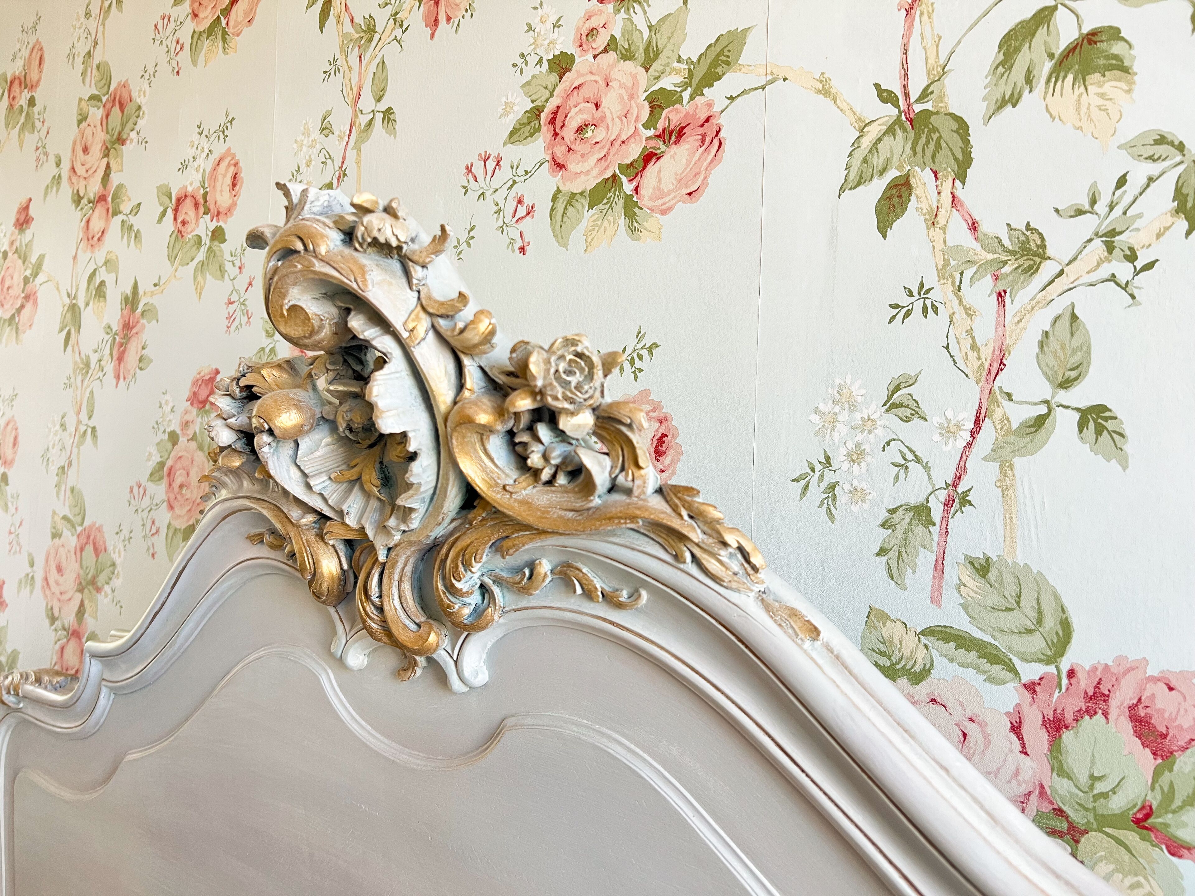 Una pared con papel tapiz floral y un cabecero decorativo y ornamentado.