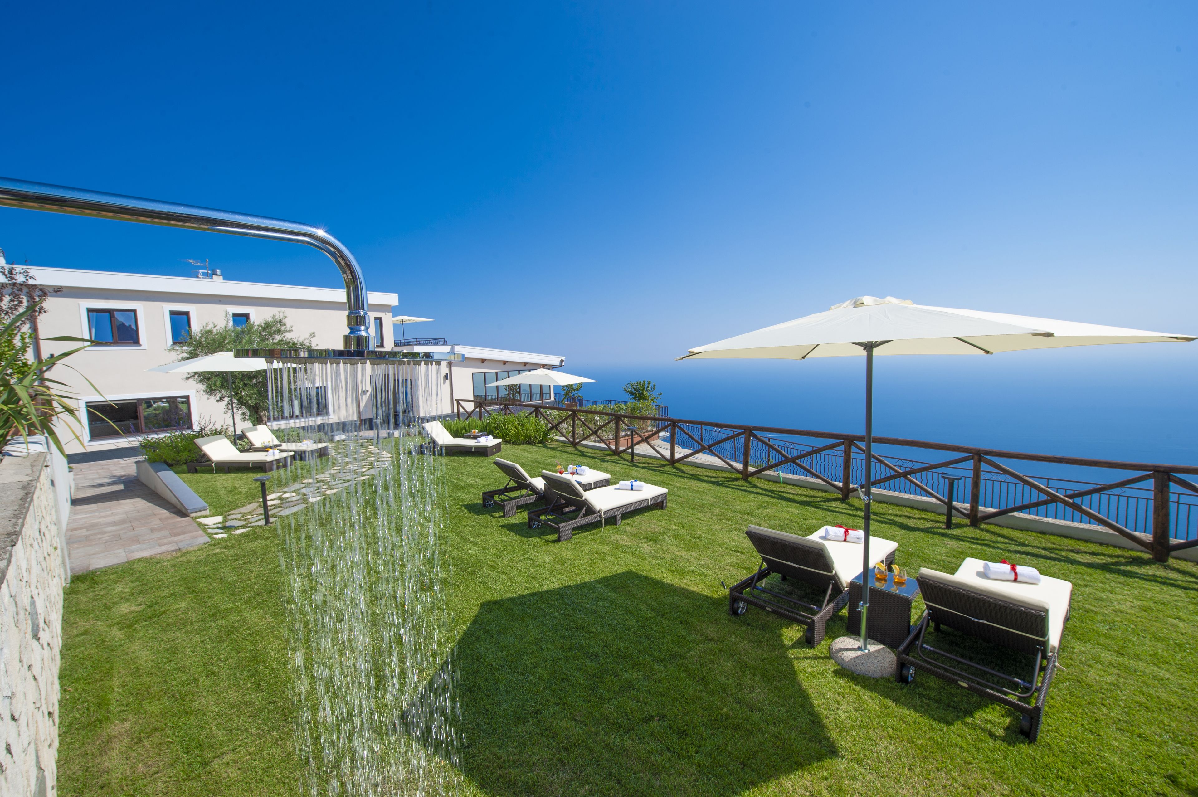 Eine Dachterrasse mit freiem Blick auf den Ozean, einem Wasserspiel und Außenmöbeln.