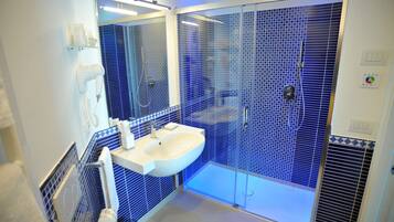 A bathroom with a white sink, a mirror, and a shower with blue-tiled walls.