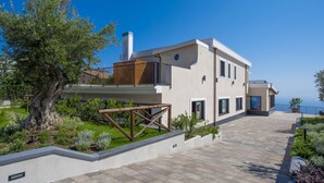 A modern two-story house with a balcony, a large tree in the front yard, and a view of the sea. - Villa Paradise Resort (Agerola)
