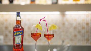 A bottle of Aperol and two glasses with straws and lemon slices.