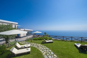 A modern outdoor patio with lounge chairs, umbrellas, and a stone pathway.