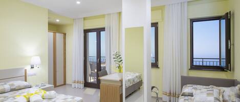 Habitación de hotel con dos camas, un escritorio, una silla, un balcón con vistas y un espejo grande.
