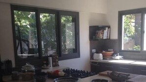Una cocina con isla central, ventanas amplias y vista a la vegetación exterior.
