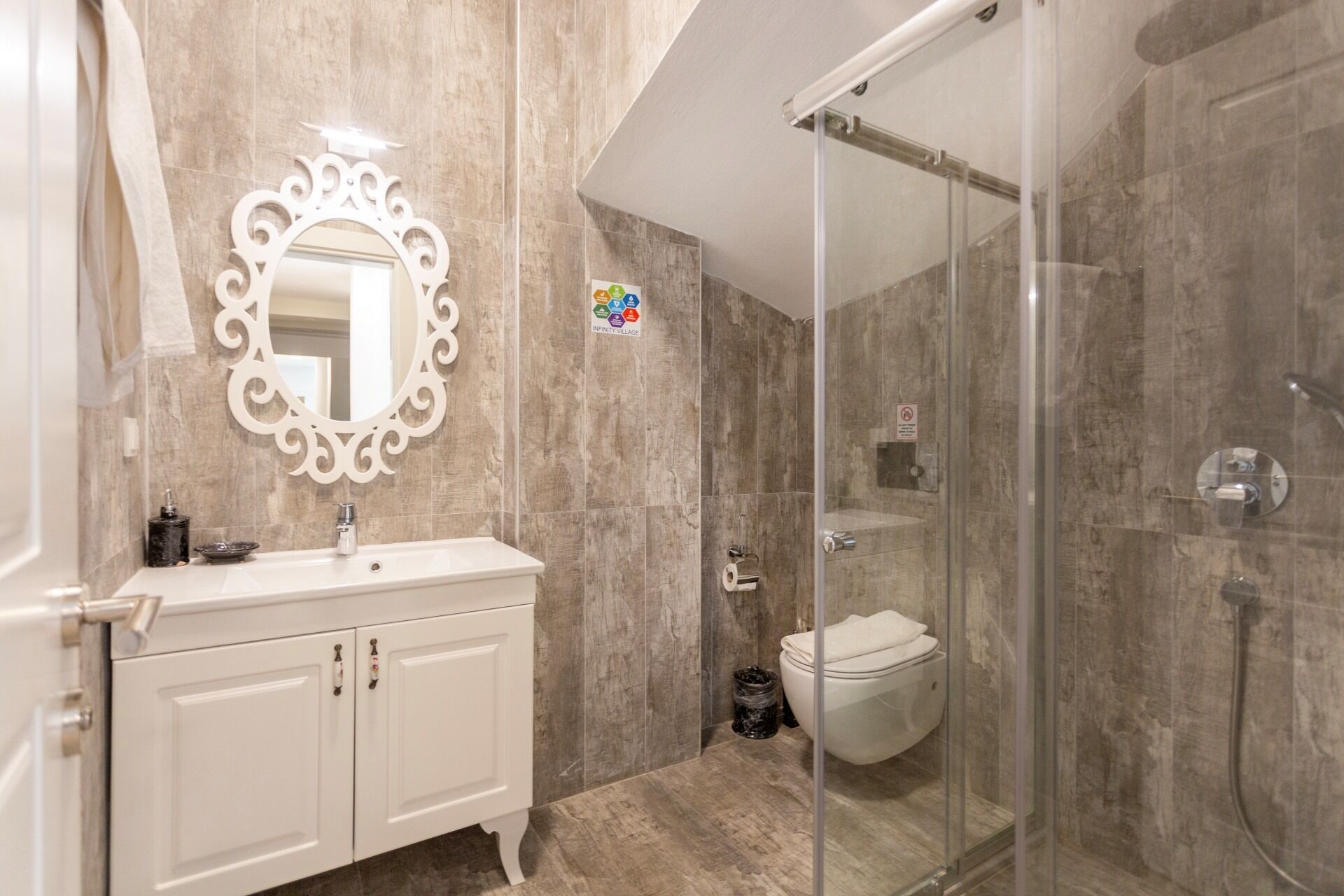 Un baño moderno con tocador blanco, un espejo grande y cabina de ducha con mampara de vidrio.