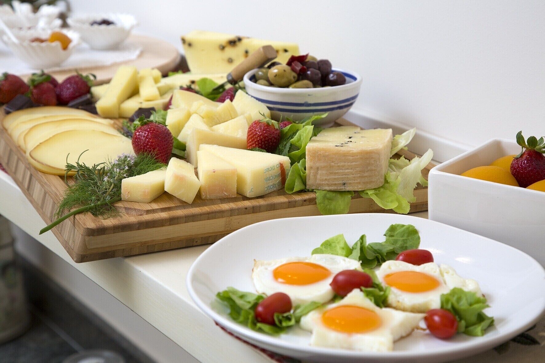 A cheese board with various cheeses, fruits, and olives.