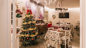 Un coin repas décoré d’un sapin de Noël, de nappes à motifs floraux et d’un lustre.