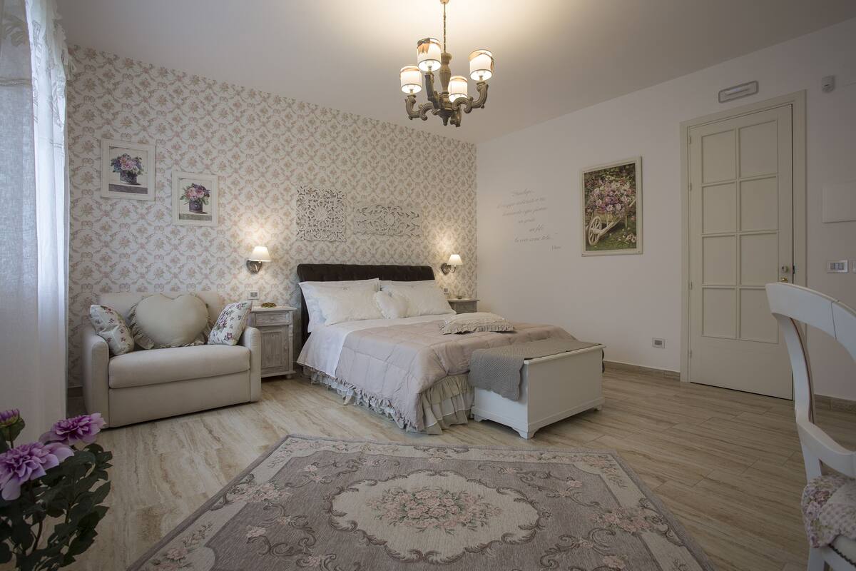 Une chambre à coucher avec un lit, des tables de chevet, une chaise, un tapis et une porte.