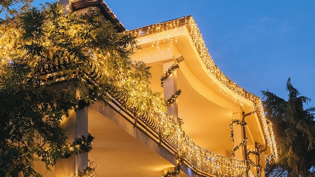 Un bâtiment à la façade incurvée, décorée de guirlandes lumineuses et de verdure.