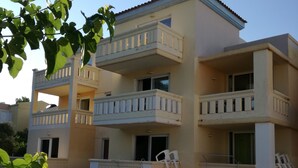 A multi-story building with balconies, a swimming pool, and lounge chairs. - Marianthi studios (Chania)