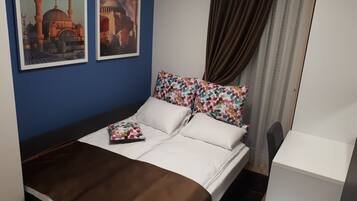 A neatly made bed with white and brown bedding, a colorful floral pillow, and a framed picture of a building on the wall.