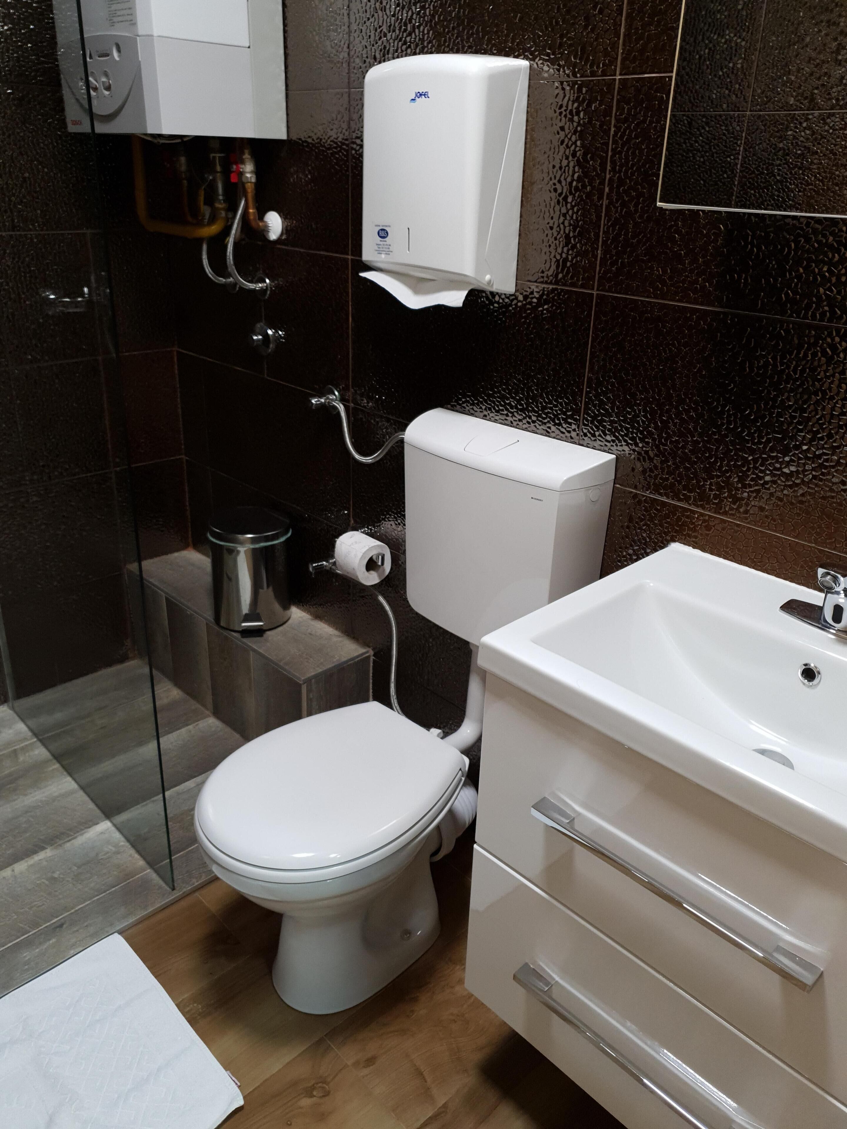 Een moderne badkamer met toilet, wastafel en douche.