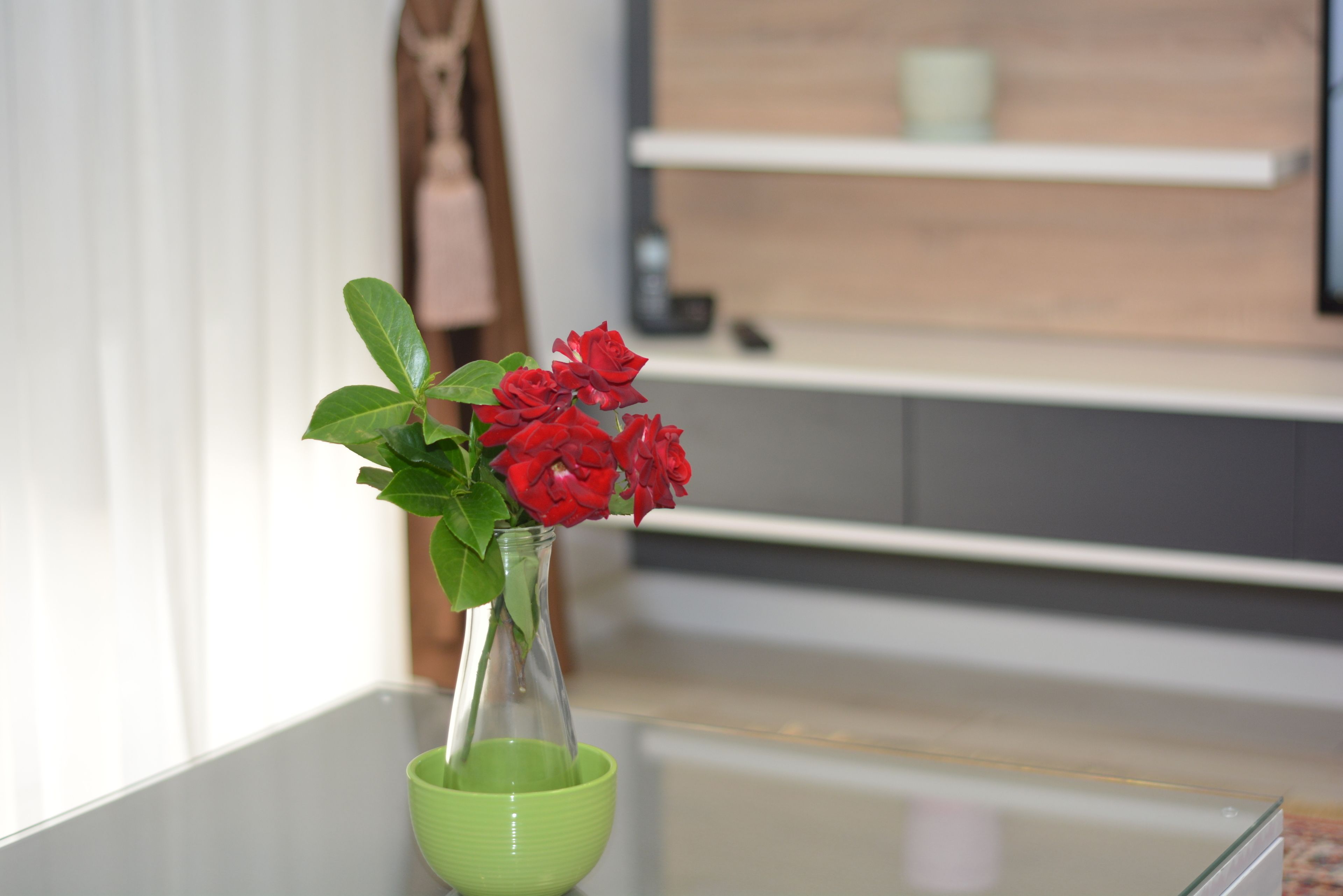 Duidelijk zicht op een vaas met rode bloemen op een glazen tafel.