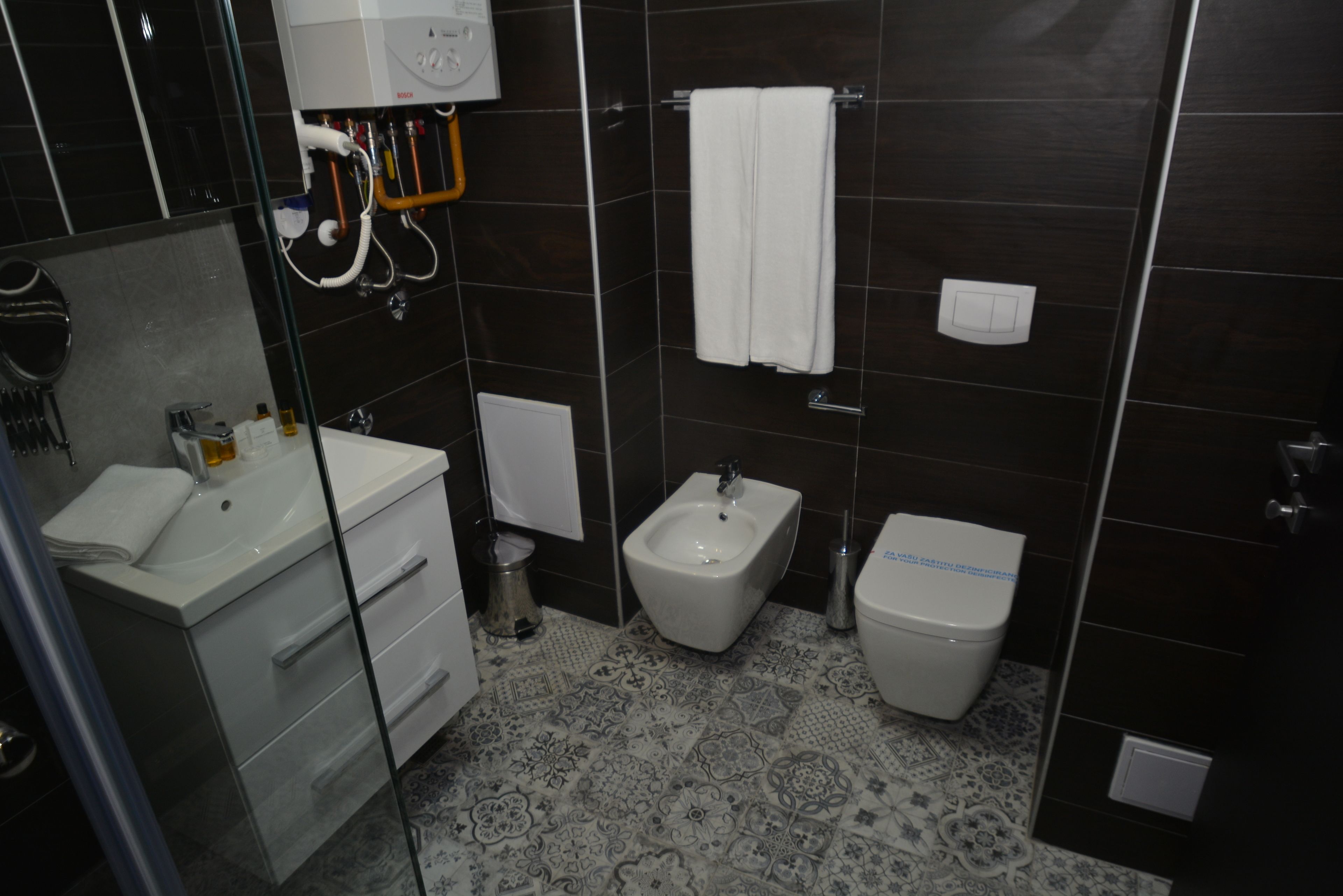 A bathroom with a sink, bidet, toilet, and a towel rack.