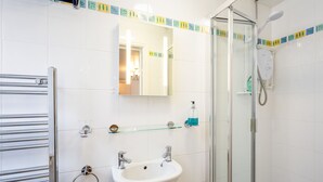 A modern bathroom with a glass shower enclosure, a white sink, and a mirror above it. - Stratford Studios (Stratford-upon-Avon)
