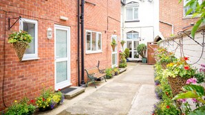 A narrow alleyway with a brick building on the left, a white building on the right, and a bench in the center. - Stratford Studios (Stratford-upon-Avon)