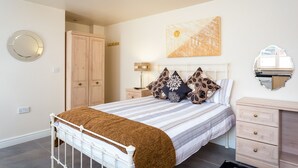 A bedroom with a bed, bedside tables, a wardrobe, a mirror, and a painting on the wall. - Stratford Studios (Stratford-upon-Avon)