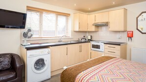 A compact kitchen with a washing machine, a stove, and a sink. - Stratford Studios (Stratford-upon-Avon)