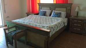 Une chambre à coucher avec un lit, une table de chevet, une chaise et une fenêtre avec des rideaux rouges.