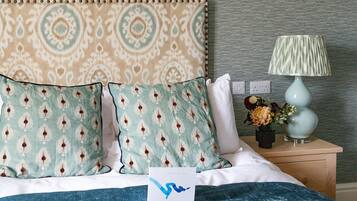 A neatly made bed with patterned pillows, a bedside lamp, and a card on the bed.
