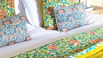 A bed with floral-patterned bedding, a gold headboard, and a bedside lamp.