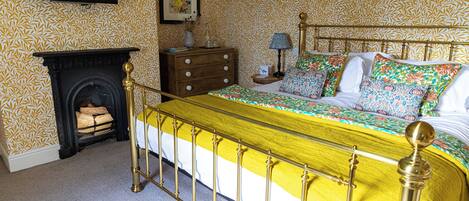 Um quarto com cama, mesa de cabeceira, cômoda, abajur e lareira.