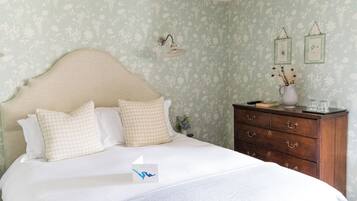 Un dormitorio con cama, cómoda y lámpara de pared.