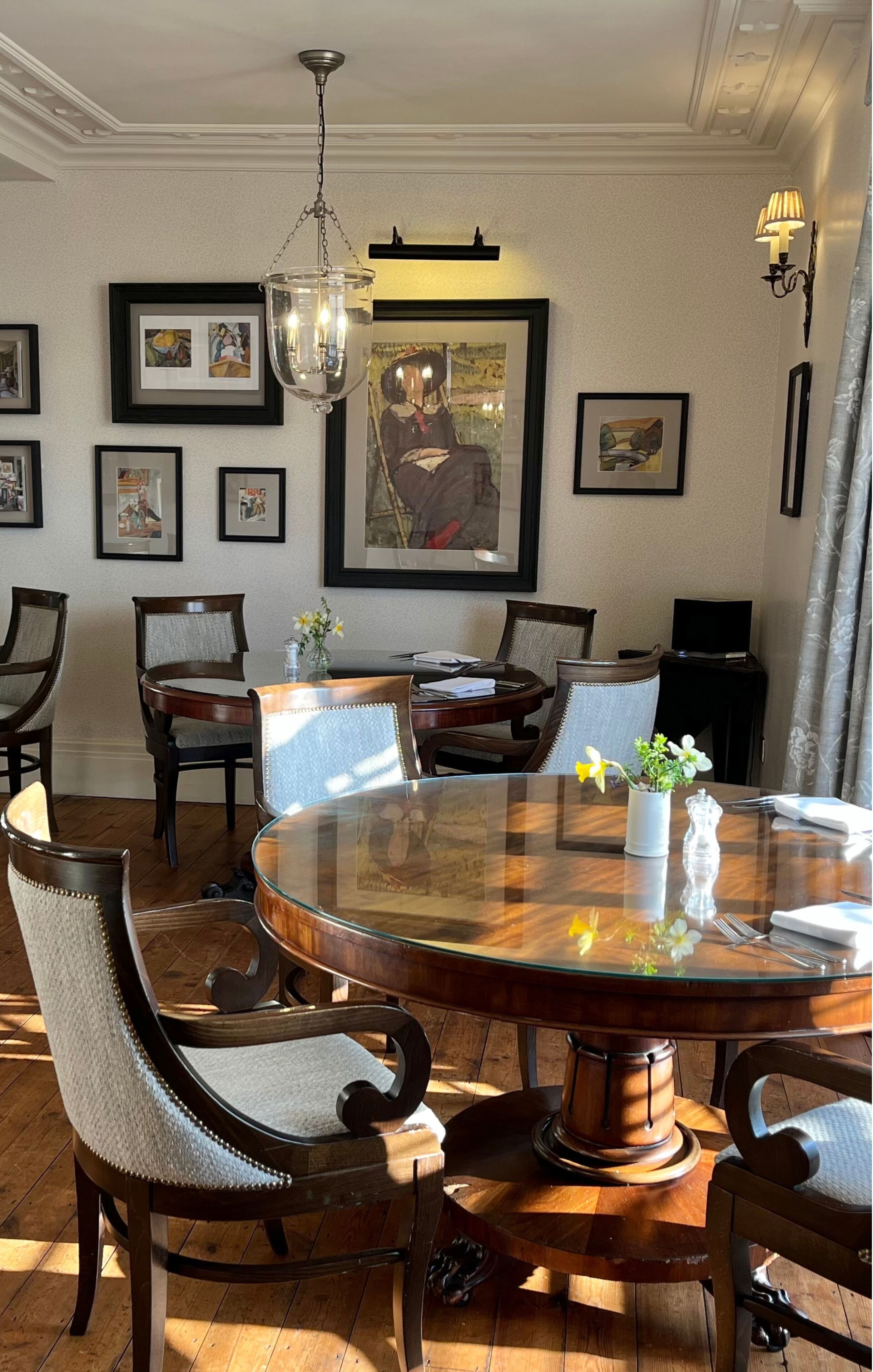 A dining area with a round glass table, wooden chairs, and a chandelier.
