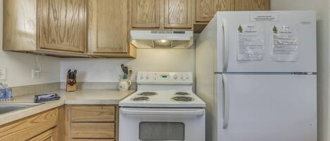 A kitchen with wooden cabinets, a white stove, and a refrigerator.