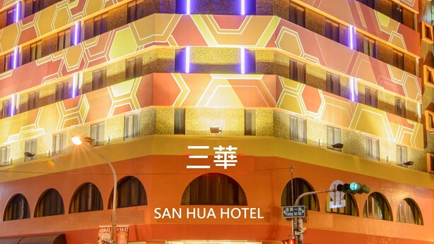 Um hotel de vários andares com fachada geométrica marcante e luzes de neon iluminadas.