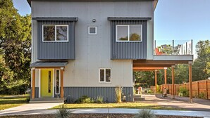 Een modern huis met twee verdiepingen, een heldergele voordeur, een overdekt terras en een omheinde achtertuin.
