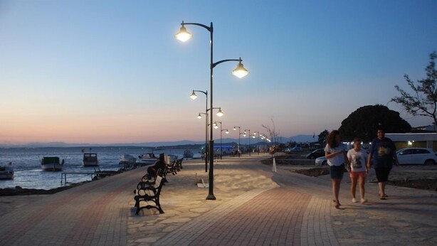 Un paseo marítimo con bancos e iluminarias.