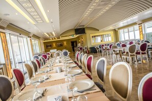 A long dining table set with chairs, a chandelier, and a large window. - Altin Otel (Ayvalik)
