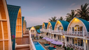 Un resort con varias cabañas sobre el agua, una piscina y zonas de estar al aire libre.