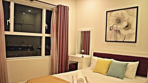 A hotel room with a bed, a nightstand, a mirror, and a window with curtains.