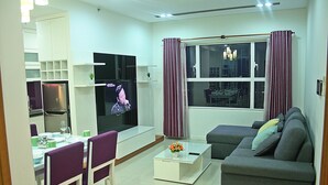 A modern living room with a sofa, a coffee table, and a dining area with chairs and a table.