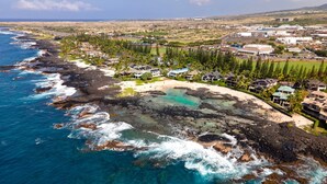 An aerial view of a coastal area with a beach, rocky shoreline, and residential buildings. - 🏖️Gorgeous Ocean Front Estate | Gated Community | Walk to Town (Kailua Kona)