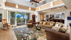 A spacious living area with a high ceiling, a large window, and a ceiling fan. - 🏖️Gorgeous Ocean Front Estate | Gated Community | Walk to Town (Kailua Kona)