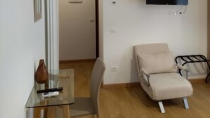 A modern living room with a flat-screen TV, a glass table with a remote, a beige sofa, and a wooden floor. - San Polo Star (Venice)