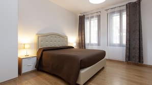 A bedroom with a bed, bedside tables, and a window with curtains. - San Polo Star (Venice)