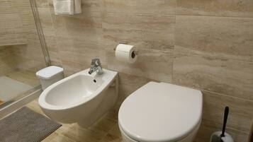 Une salle de bain équipée d’un bidet, de toilettes et d’un porte-serviettes.